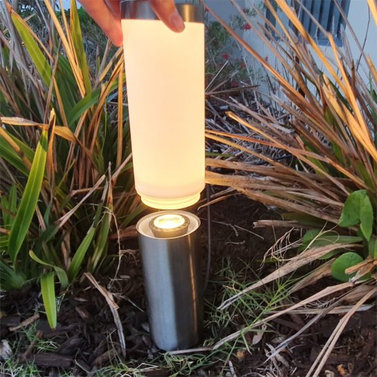 A bollard light with top glass removed revealing the light bulb inside the middle