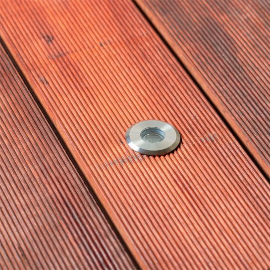 An Elluminate deck light installed in decking during the day