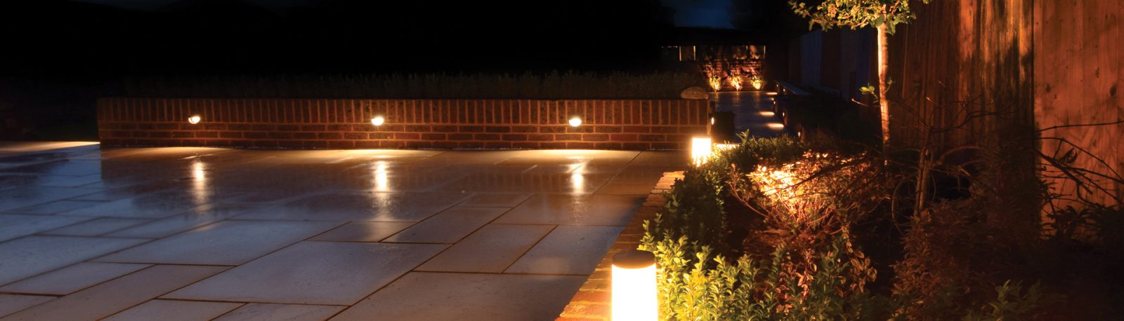 Elluminate lights casting a glow across some pavers in garden at night